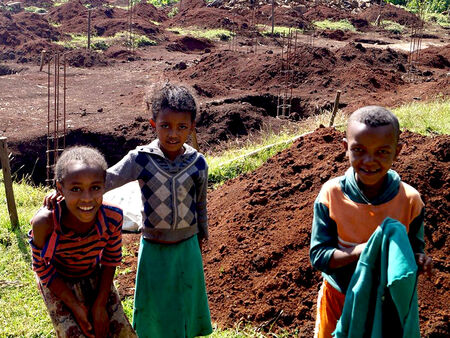 Trys Etiopijos vaikai priešais naujos mokyklos statybų aikštelę