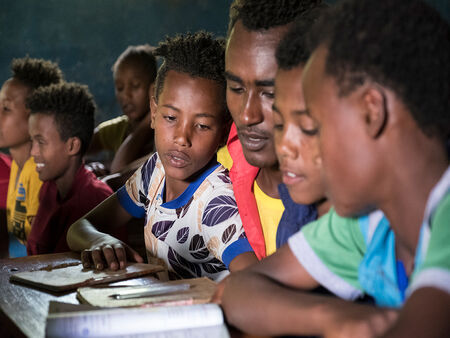 Mai mulți copii etiopieni se uită într-un manual