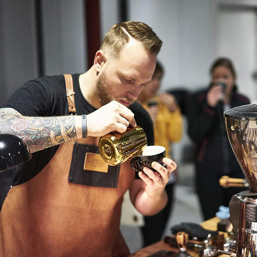 Barista Gregory Raymond gießt Latte Art in einen Cappuccino