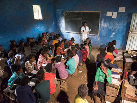 Widok na pracownię etiopskiej szkoły z prowadzącą lekcję nauczycielką przed wieloma uczniami