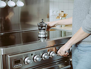 A stovetop espresso maker being put on the stove and heated up