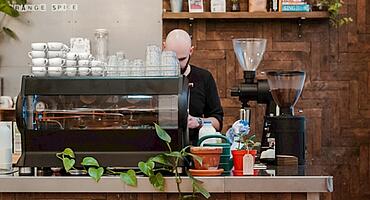 Un barista prépare le café sur une machine à porte-filtre.