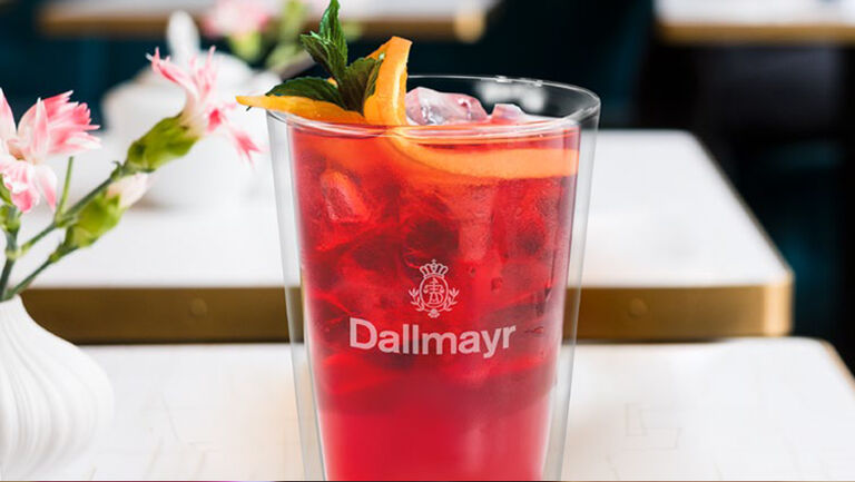 Tè freddo Dallmayr in bicchiere di vetro guarnito con arancia e menta