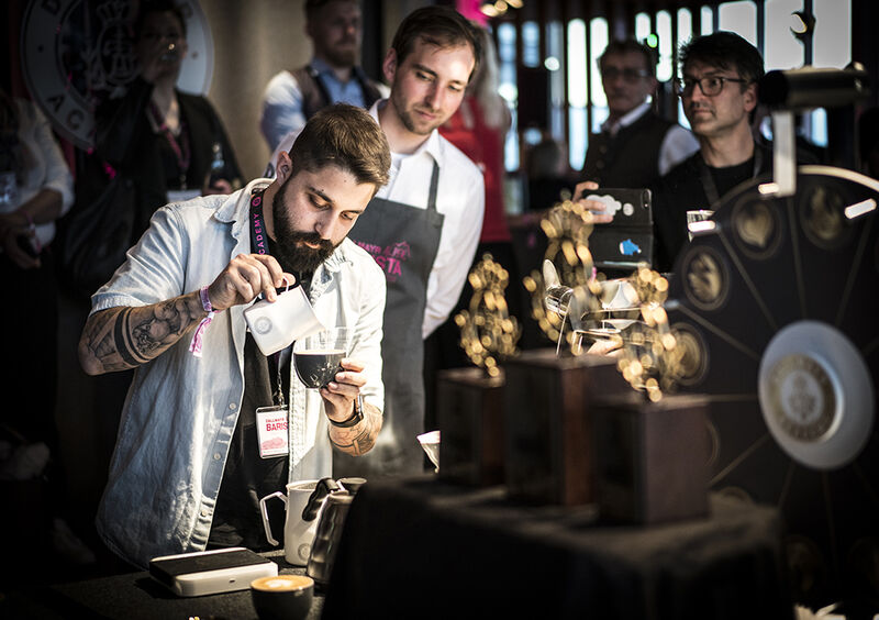 Barista Michalis Katsiavos gießt Latte Art in einen Dallmayr Cappuccino