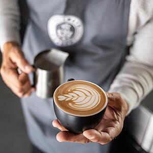 A barista showing a latte-art motif
