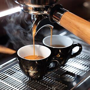 Freshly brewed espresso flowing from a portafilter espresso machine into Dallmayr espresso cups