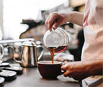 Barista schenkt Filterkaffee in Tasse