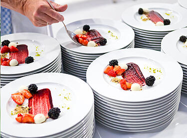 Catering Team arrangiert Gericht auf weißen Tellern für ein Event