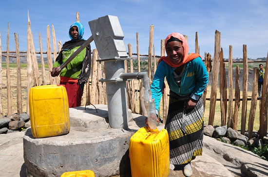 Frauen am Brunnen beim Wasser holen