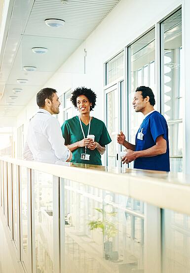 Drei Krankenhausmitarbeiter besprechen sich im Krankenhausflur