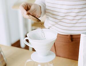 Kaffee wird in Keramikfilter mit Löffel gegeben
