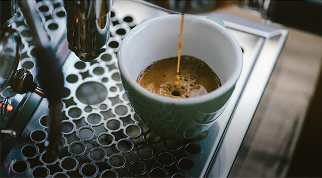 Frisch gebrühter Espresso läuft aus einem Siebträger in eine Espresso Tasse