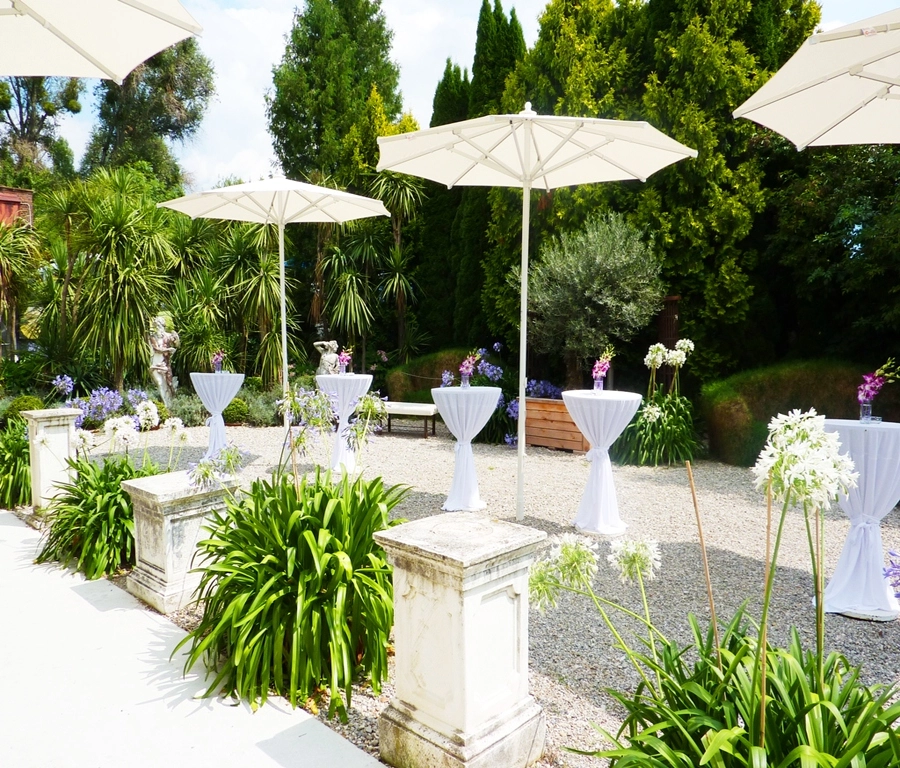 Außenbereich eines Catering Events mit Stehtischen Blumen und weißen Schirmen