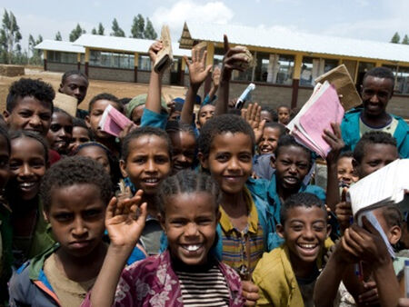 Daug besijuokiančių Etiopijos vaikų priešais naująją mokyklą