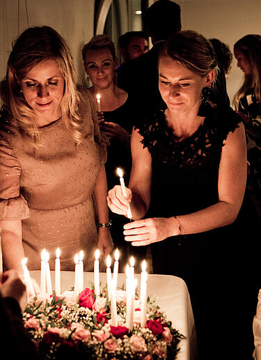 Party Gäste platzieren Kerzen auf der Geburtstagstorte