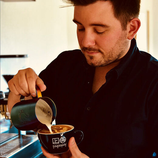 Barista Daniel Gerlach gießt Latte Art in einen Cappuccino