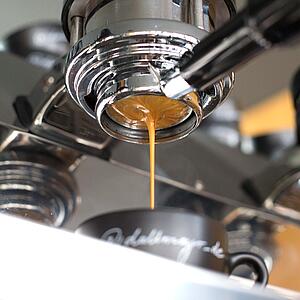 Espresso läuft aus der Brühgruppe in Dallmayr Tasse