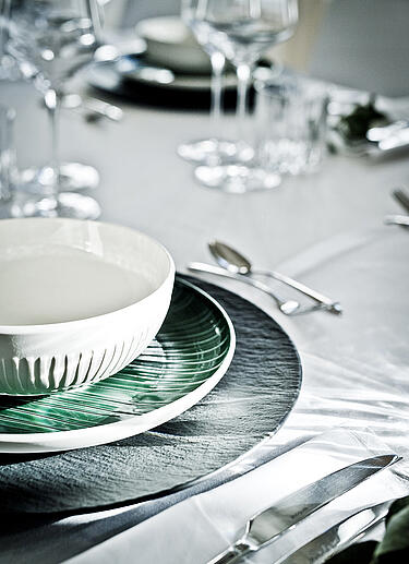 Gedeckter Tisch mit grünem und weißem Geschirr
