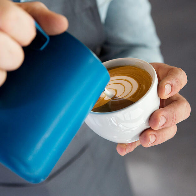 Barista giesst Latte Art in eine Cappuccino Tasse