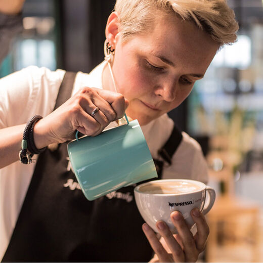 Barista Agnieszka Rojewska gießt Latte Art in einen Capuccino