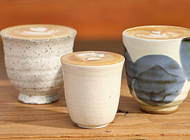 Drei Tassen mit Latte Art Motiven