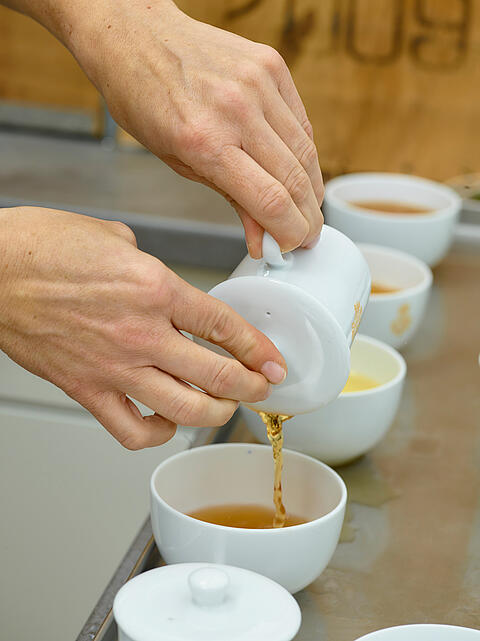 Aufgebrühter Tee wird in Probierschale gegossen