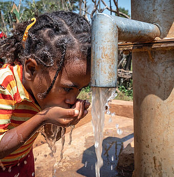 Etiopė mergaitė iš šulinio geria švarų geriamąjį vandenį