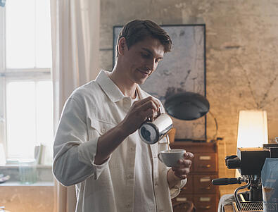 Pruunijuukseline mees kallab tassi latte art'i