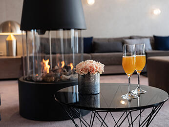 Salonek v hotelu Öschberghof se dvěma nápoji na malém stolku před krbem