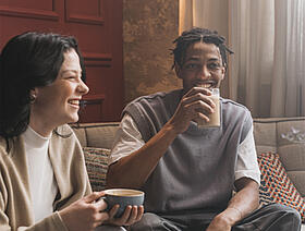 Twee mensen die in de woonkamer van een kopje koffie genieten