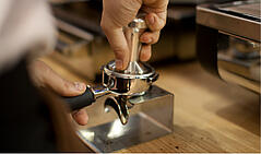 Ground espresso is pressed down into the portafilter with a tamper