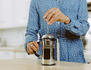 The plunger of a French press being pushed down lightly