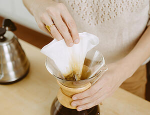 Filter mit fertig extrahiertem Kaffeepulver wird aus Chemex entfernt
