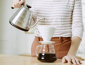 Water being poured into a coffee dripper and coffee flowing into the pot