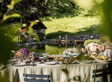 Event Location am Wasser mit sommerlich gedecktem Tisch, Häppchen und Blumen