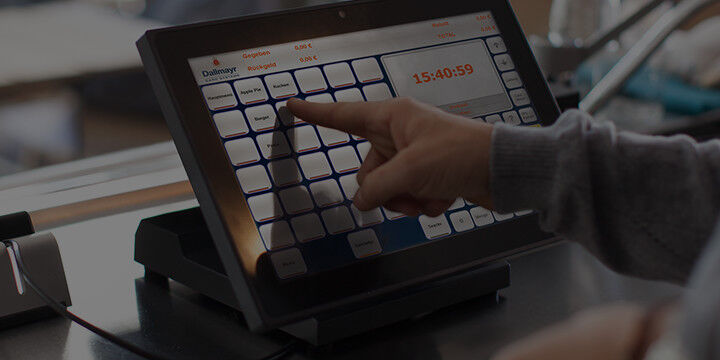Mitarbeiter bedient Touchscreen eines Dallmayr pay Kassensystems