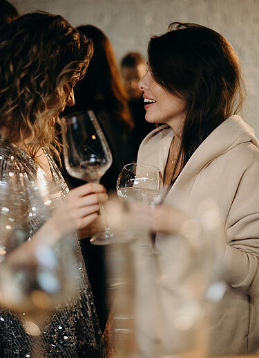 Zwei Frauen unterhalten sich und trinken auf einem Event Wein