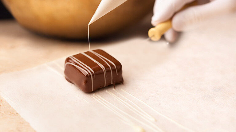 Vollmilchschokoladenpraline wird mit weisser Schokolade dekoriert