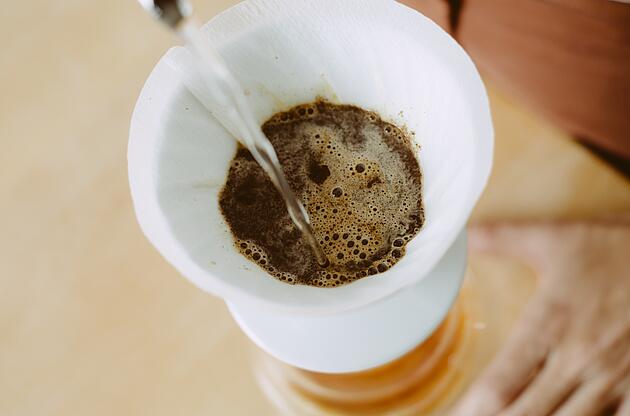 Wasser wird auf Kaffeemehl im Handfilter gegossen