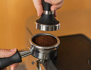 Ground coffee being tamped in a portafilter