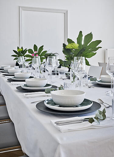 Gedeckter Tisch für ein Event in weiß mit grünen Farbakzenten