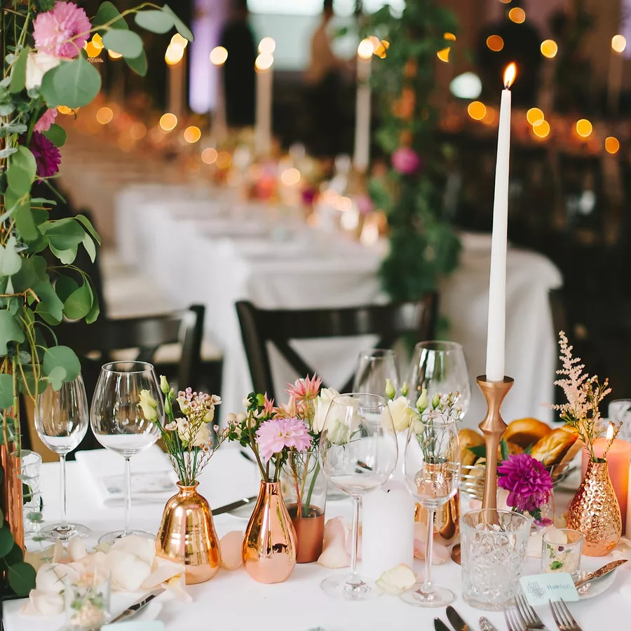 Gedeckter Tisch mit rosegolgenen Vasen und Blumendekoration