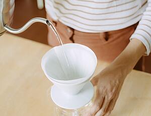 Hot water being poured into a ceramic coffee dripper containing filter paper
