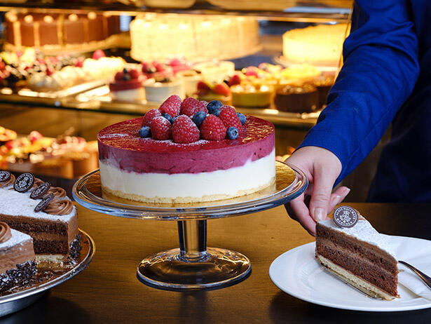 Zamestnanec spoločnosti Dallmayr podáva kúsok koláča v kaviarni Café Bistro