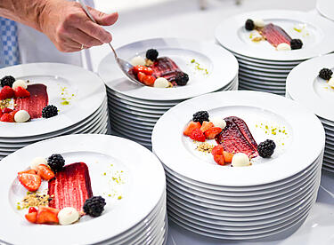 Nachtisch mit Beeren wird vom Catering Team auf weißen Tellern angerichtet