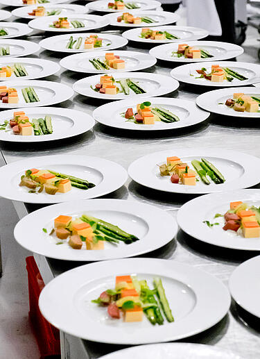 Gerichte mit Spargel auf weißen Tellern stehen bereit für das Catering Service Personal