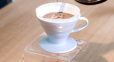 Keramikhandfilter mit Kaffeemehl wird übergossen mit Wasser