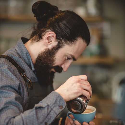 Barista Ali Yagci gießt Latte Art in einen Cappuccino