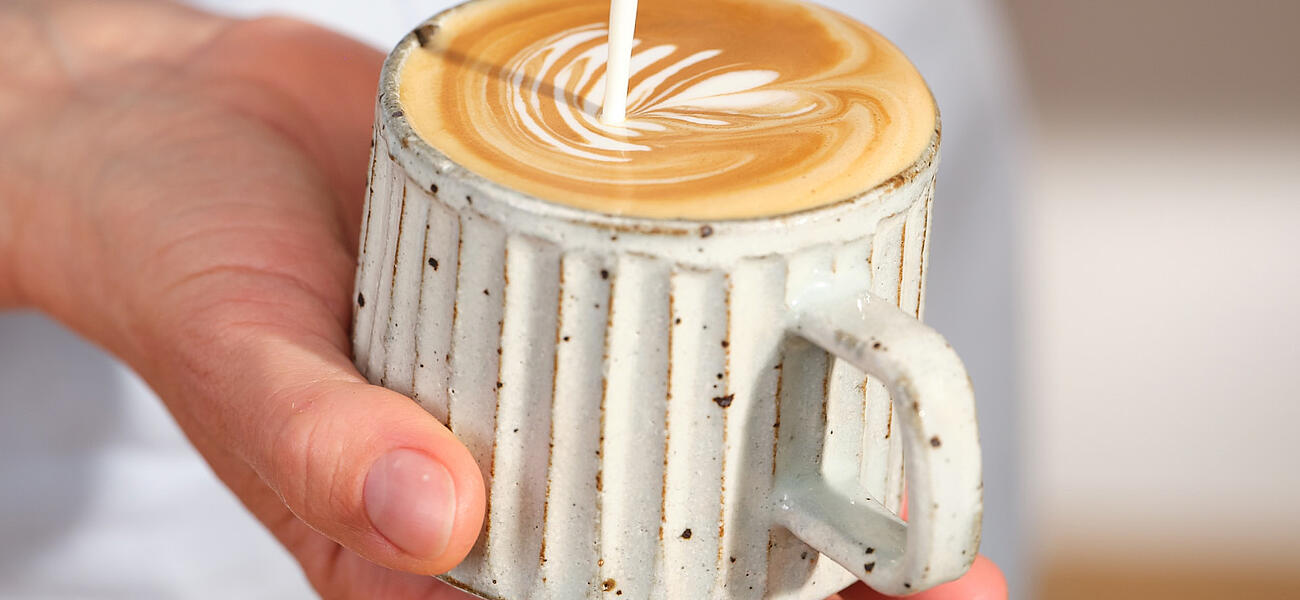 Barista gießt Latte Art in eine rustikale Tasse